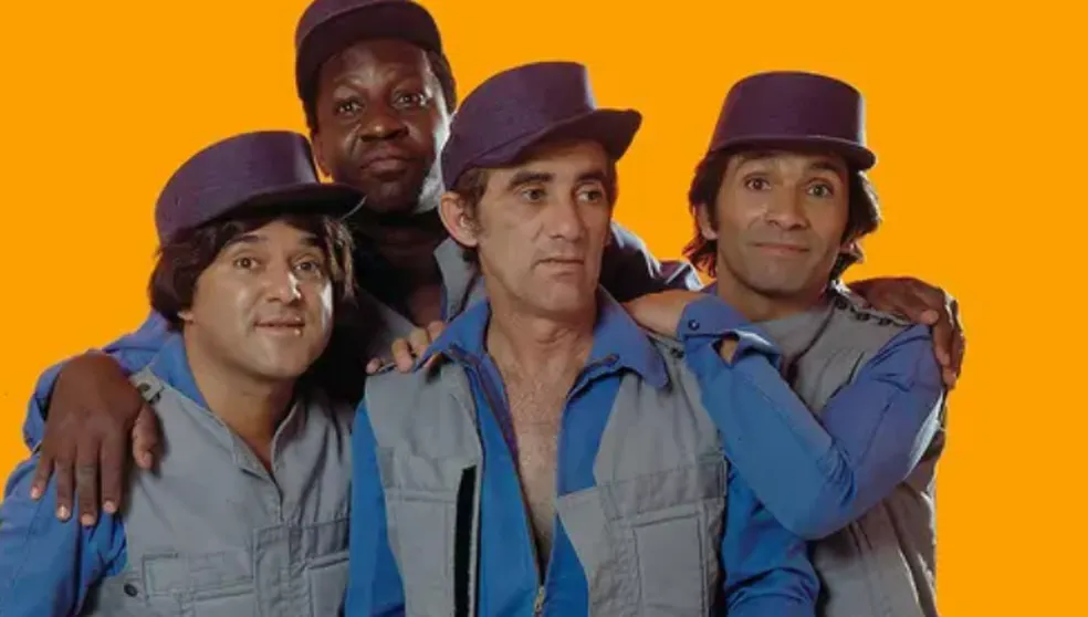 Ded&eacute; Santana sentado em um camarim de circo, em frente a um espelho com l&acirc;mpadas amareladas.