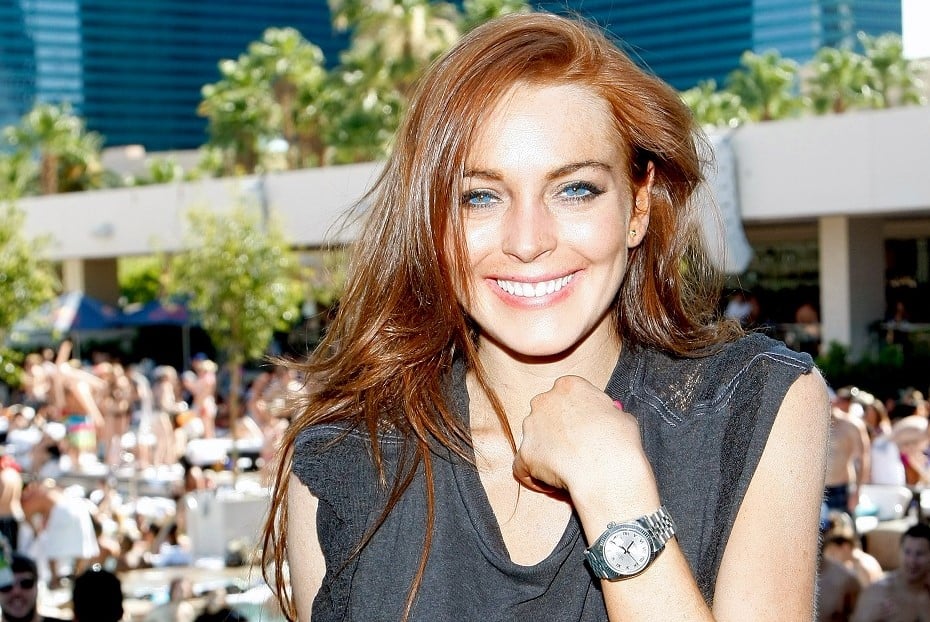 Uma imagem dividida. De um lado, Lindsay Lohan no auge dos anos 2000, saindo de um carro esportivo cercada por flashes brancos agressivos de dezenas de c&acirc;meras.